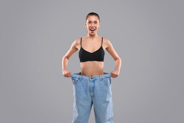 Foto mujer de dieta asombrada en jeans grandes