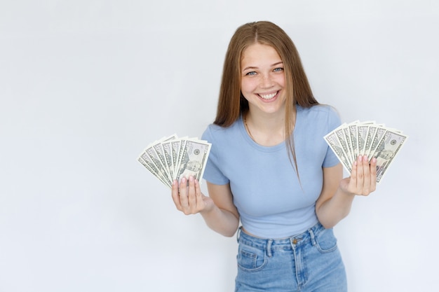 Mujer con dinero sonríe sobre fondo blanco.