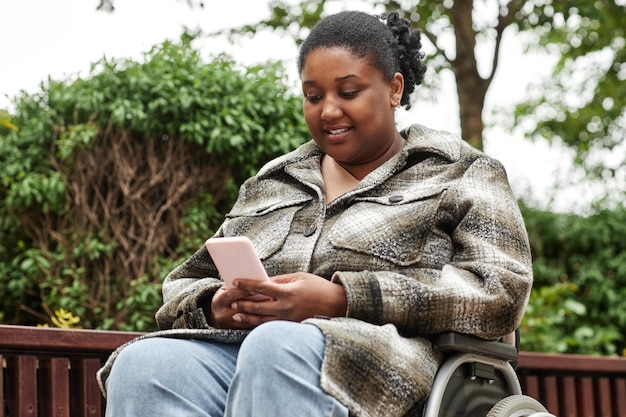Mujer con discapacidad usando teléfono al aire libre