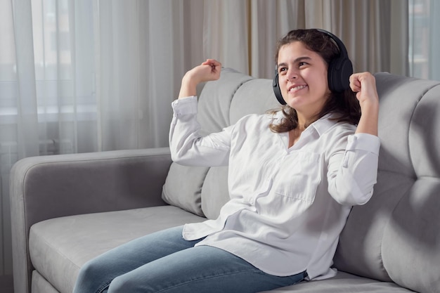 Mujer discapacitada en auriculares escucha música bailando en el sofá