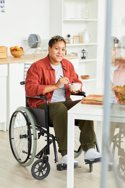 Mujer discapacitada comiendo en la cocina