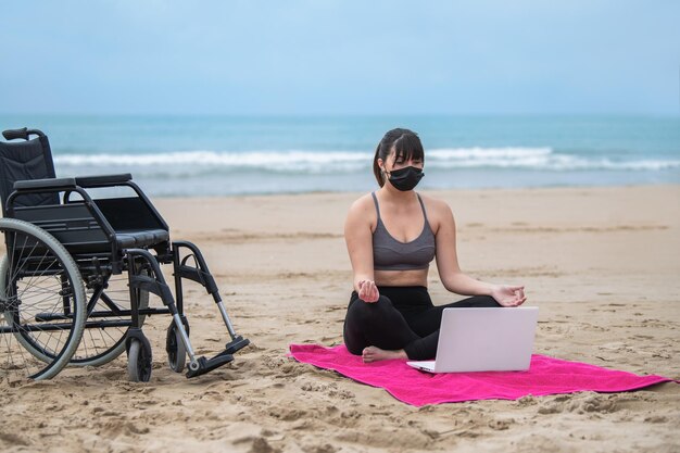 Foto mujer discapacitada practicando yoga en la playa