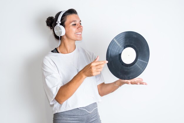 Una mujer con un disco en la mano y auriculares escuchando música.