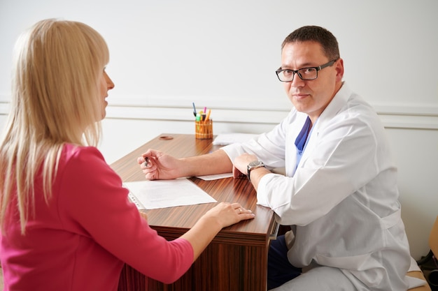 Mujer discutiendo cirugía plástica con el médico en una clínica moderna