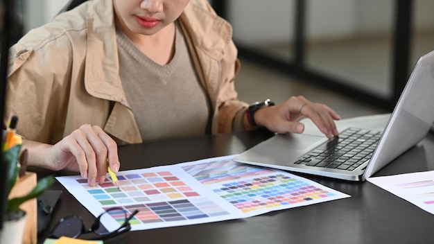 Mujer de diseñador gráfico de tiro recortada que trabaja con paleta de colores en el escritorio de oficina.