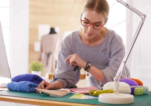 Foto mujer diseñadora de moda estadounidense que trabaja en el taller