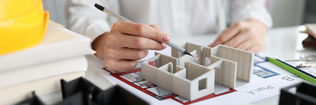 Mujer diseñadora mostrando modelo d de casa en primer plano de estudio