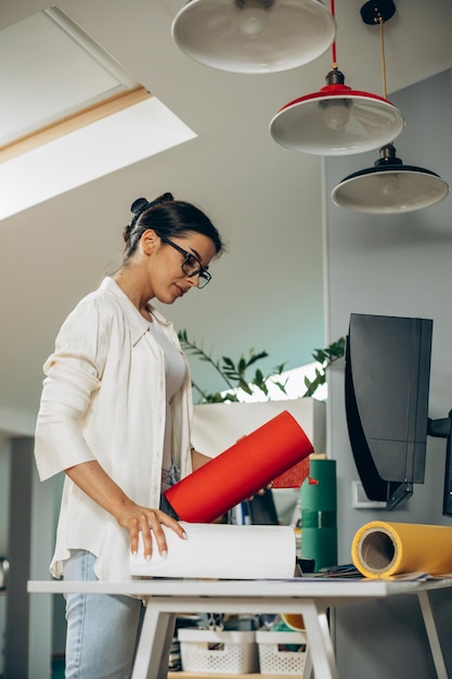 Mujer diseñadora con papel de colores en una oficina.