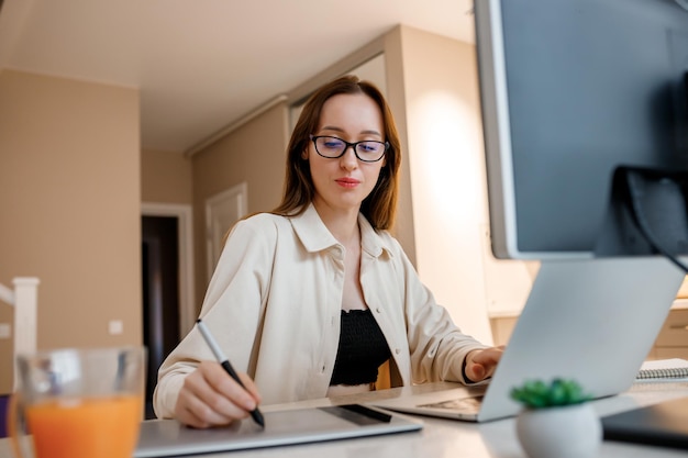 Mujer diseñadora trabajando en la oficina en casa con nuevas ideas Joven mujer independiente feliz trabajando en un proyecto viendo películas en la computadora estudiando blogs descansando y chateando en línea