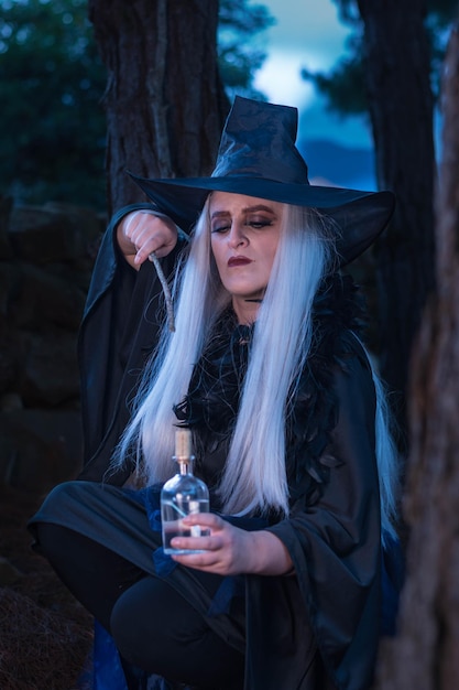 Mujer disfrazada de bruja posando en el bosque al atardecer Hechizos de magia y brujería