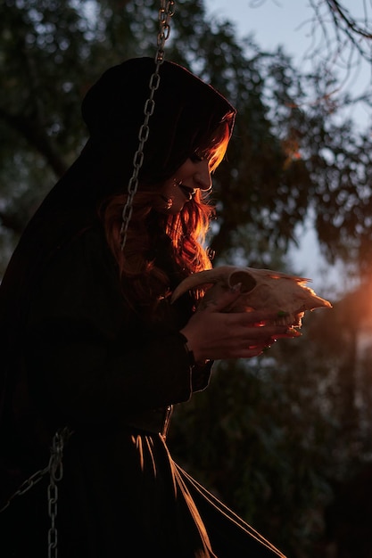 Mujer disfrazada de bruja sosteniendo una calavera en sus manos