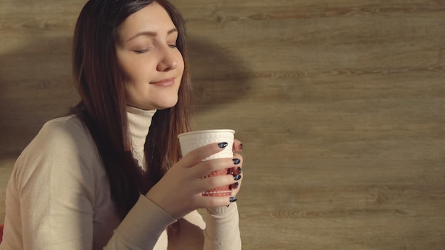 La mujer disfruta de beber café recién hecho en un vaso de papel.