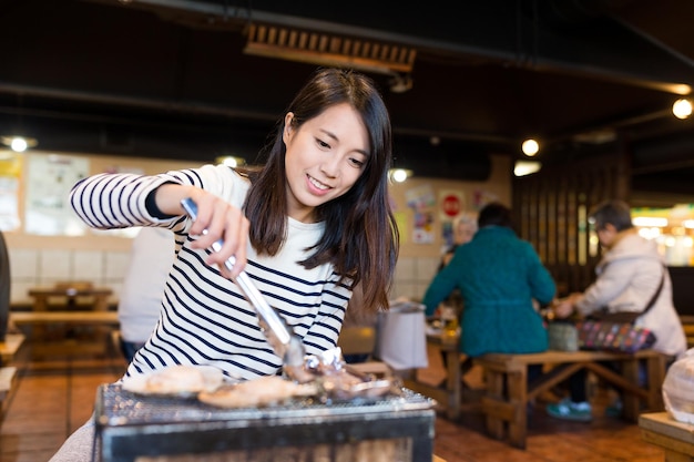 La mujer disfruta de la comida a la parrilla en el restaurante