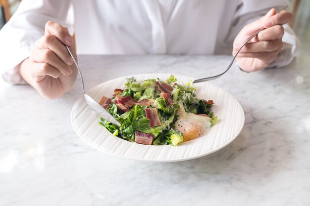 mujer disfruta comiendo ensalada tibia en la mesa en el restaurante