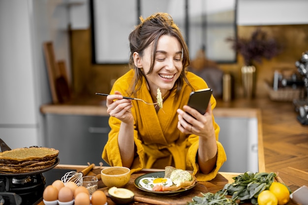 La mujer disfruta del desayuno en la cocina por la mañana