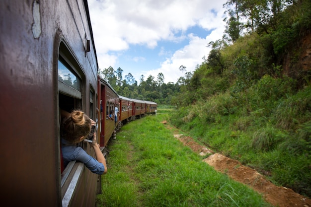 Una mujer disfruta de la naturaleza viajando en un tren en Sri Lanka