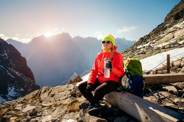 Mujer disfruta del paisaje de montaña y el agua potable después de subir