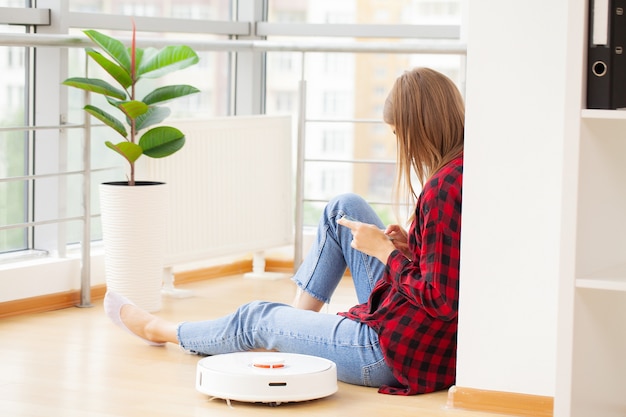 La mujer disfruta del trabajo de un robot aspirador inteligente.