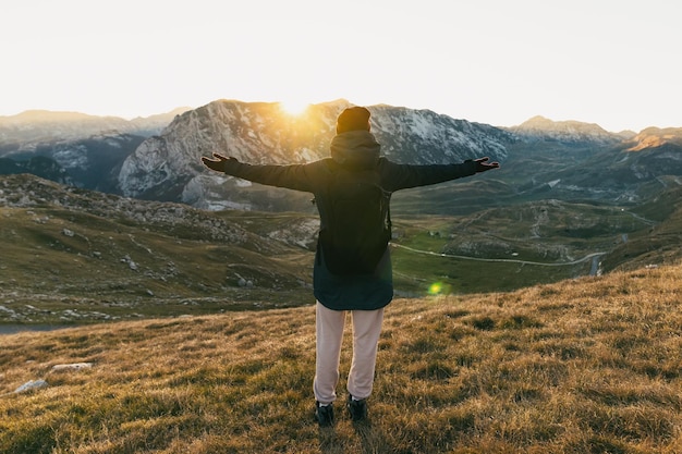 Una mujer disfruta de una vista a la montaña al atardecer