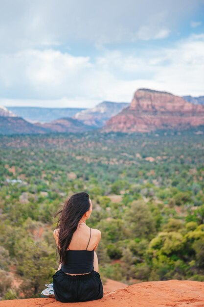 Una mujer disfruta de la vista del paisaje de Sedona desde la cima de la ruta de senderismo Bell Rock famosa por sus muchos vórtices de energía y rocas rojas