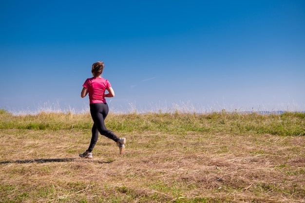 mujer disfrutando del aire fresco en un concepto de estilo de vida saludable mientras trota en el hermoso y soleado concepto de ejercicio y fitness en el campo de montaña de verano