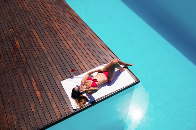 Mujer disfrutando de un baño de sol en el borde de la piscina