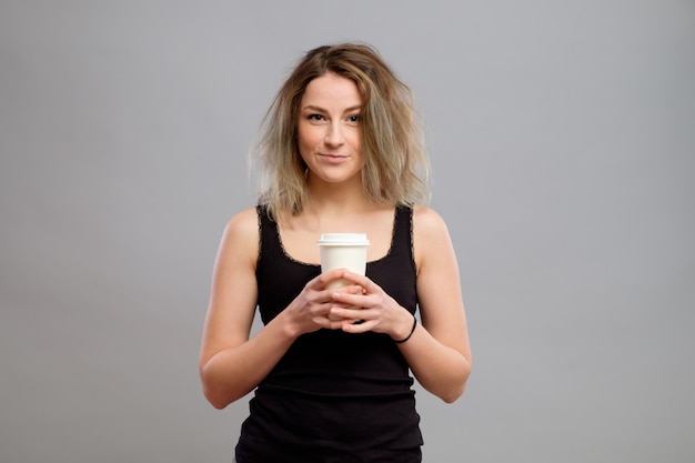 Mujer disfrutando de una bebida caliente en un vaso de papel desechable