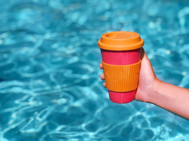 Mujer disfrutando de un café en una taza de bambú reutilizable en la piscina Cero desperdicio de café para llevar