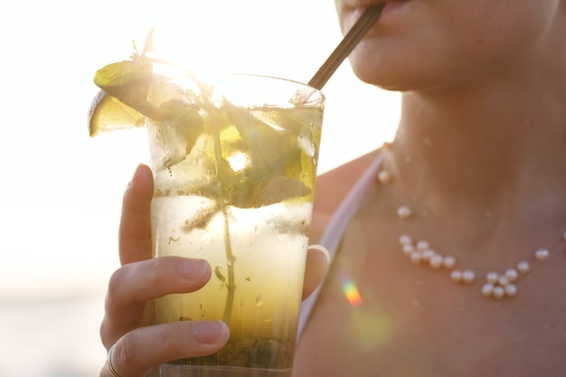 Mujer disfrutando de un cóctel mojito tropical