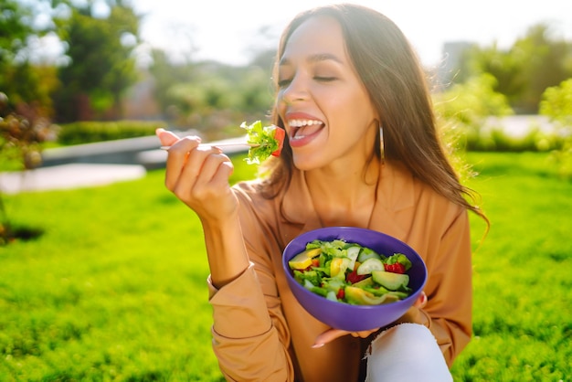 Foto mujer disfrutando de una comida saludable mujer comiendo ensalada al aire libre en un día soleado concepto picnic vegetariano