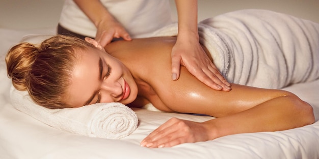 Mujer disfrutando de un masaje de hombro en el spa de salud