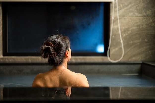 Mujer disfrutando del onsen en la bañera en el complejo