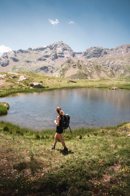 Foto mujer disfrutando del paisaje de un lago en los pirineos durante un viaje de senderismo de verano en huesca