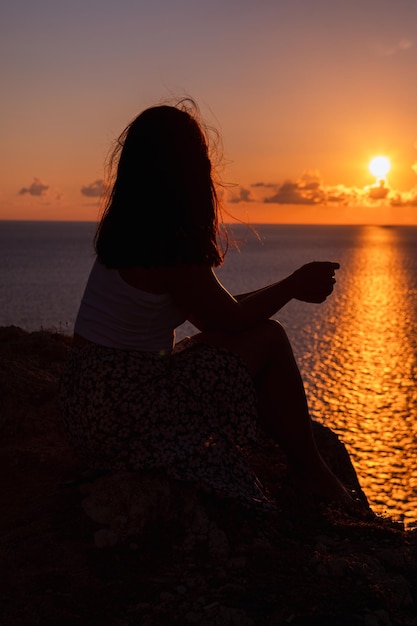 Mujer disfrutando de la puesta de sol sobre el mar vacaciones de verano