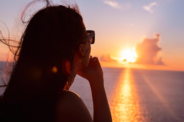 Mujer disfrutando de la puesta de sol sobre el mar vacaciones de verano