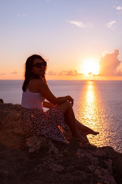 Mujer disfrutando de la puesta de sol sobre el mar vacaciones de verano