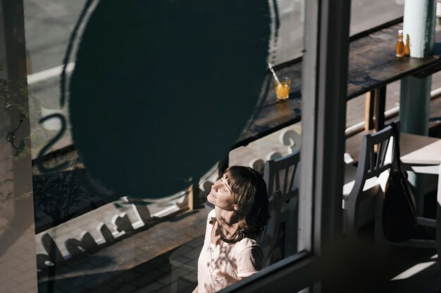 Mujer disfrutando del sol, sentada en un café.