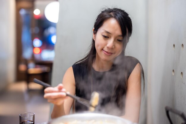 Mujer disfrutando de su olla caliente en el restaurante