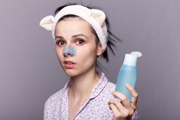 Foto mujer divertida en una banda de pelo de orejas largas sosteniendo una botella cosmética