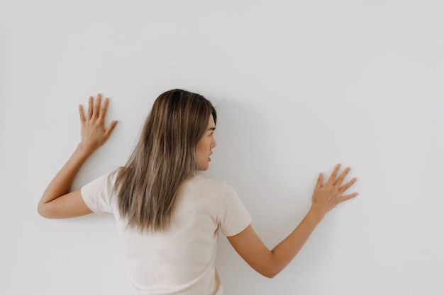 Foto mujer divertida yace en el fondo trata de espiar y escuchar por encima de la pared