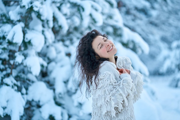 La mujer divirtiéndose caminando en el bosque de invierno cubierto de nieve