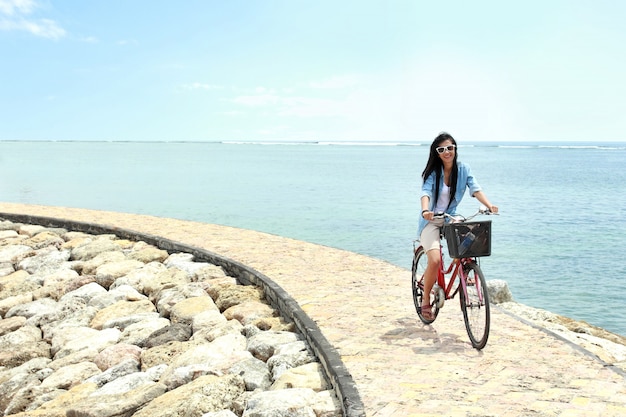 Mujer divirtiéndose montando bicicleta en la playa