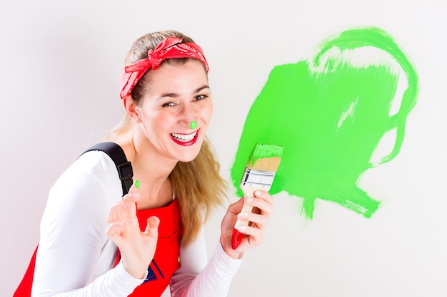 Mujer divirtiéndose pintando pared