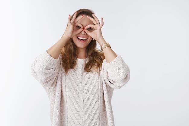 Mujer divirtiéndose tonto mostrando gafas haciendo gafas de dedo en los ojos sonriendo ampliamente jugando expresando positividad