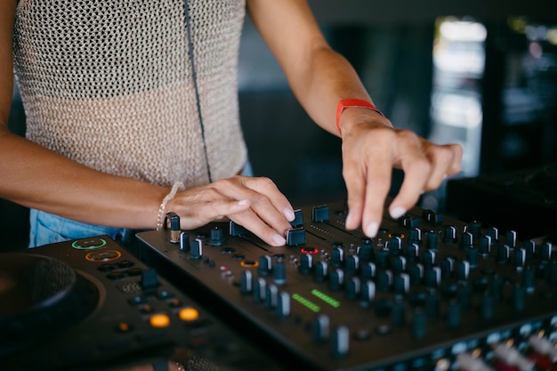 Foto mujer dj manos creando y regulando música en el mezclador de la consola de dj en un festival de música de alta calidad