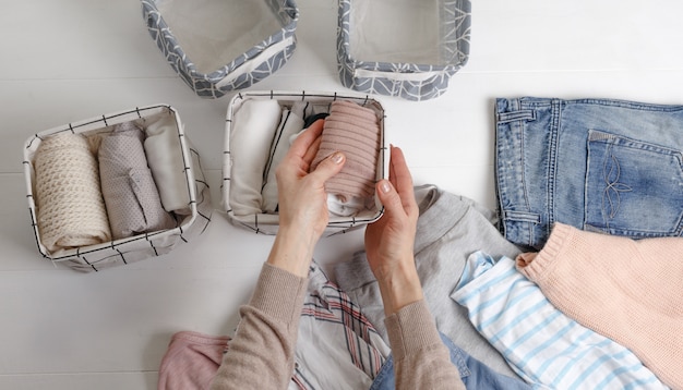 La mujer dobla cuidadosamente la ropa y la mete en cestas y cajas.