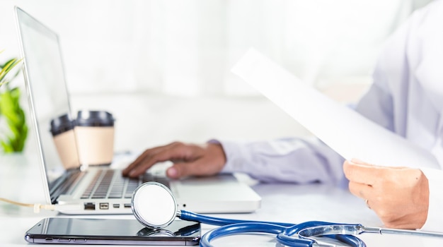 Mujer doctora escribiendo información de la prescripción del paciente del formulario de historial médico en papeleo en la computadora portátil