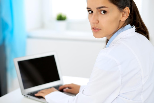 Mujer doctora con laptop en la oficina