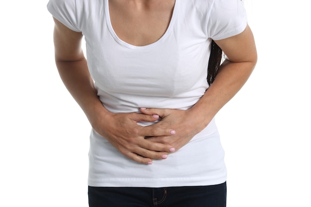 Mujer con dolor abdominal en camiseta blanca y fondo blanco. Causas del concepto de dolor abdominal inferior