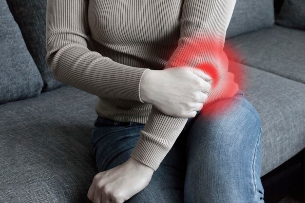 Foto mujer con dolor en el brazo mujer masajeando la mano dolorosa en el interior sosteniendo su codo que sufre de dolor de codo en casa